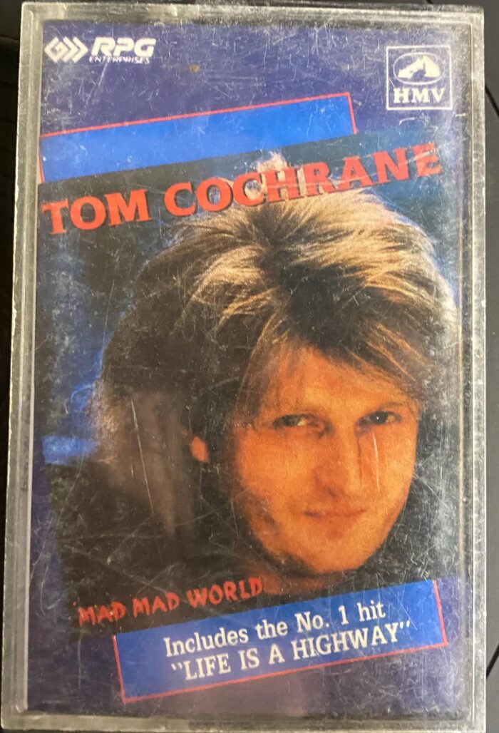 MAD MAD WORLD BY TOM COCHRANE (ENGLISH) - USED